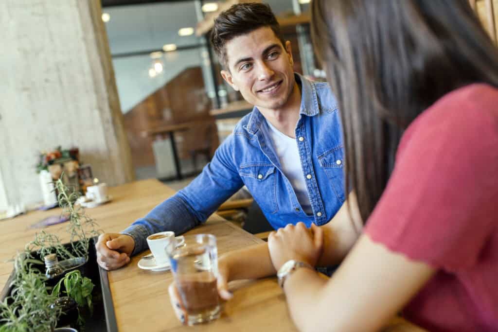 Happy young couple in restaurant waiting for food and talking